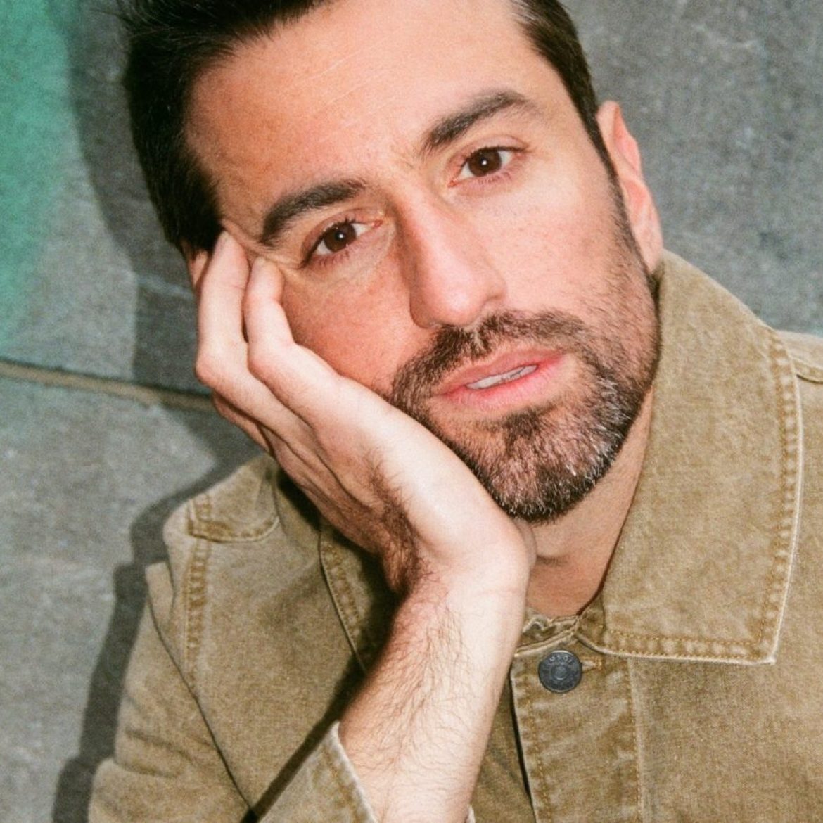 dotan leunt op zijn hand en kijkt de camera in