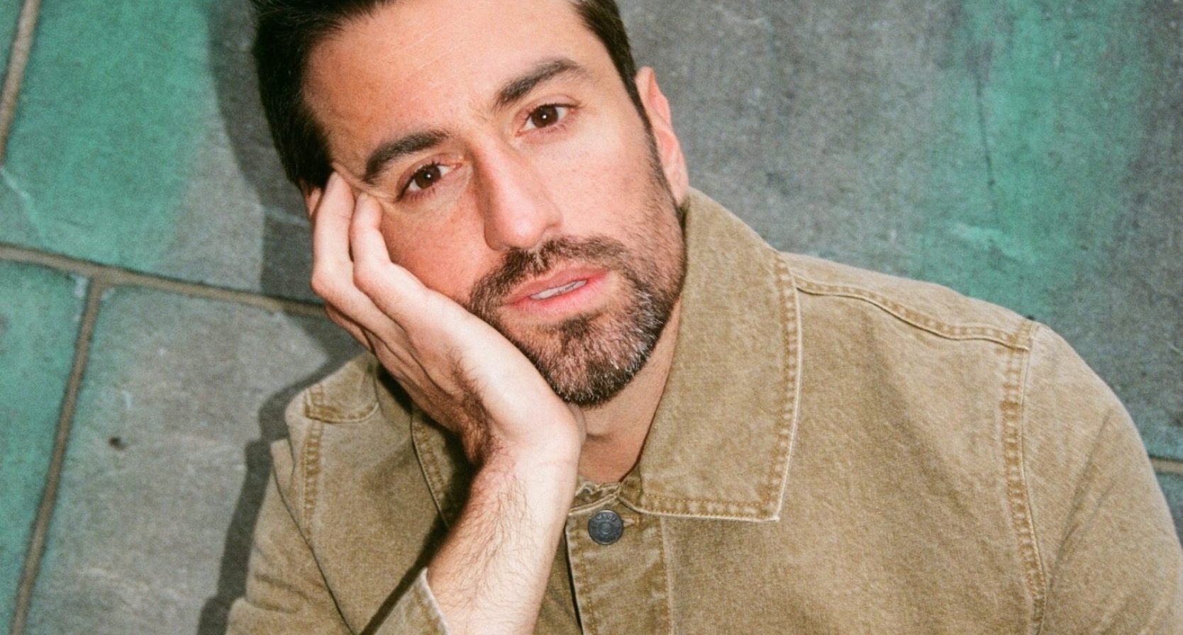 dotan leunt op zijn hand en kijkt de camera in
