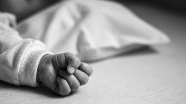 baby ligt op wit laken handje zichtbaar tbs vrouw baby