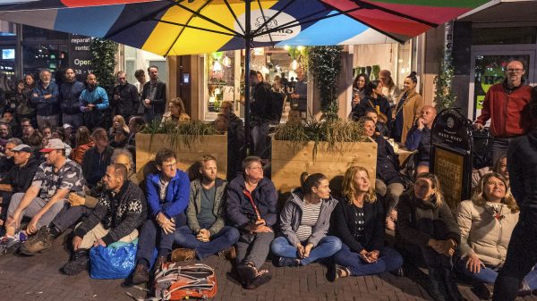 Actievoerders verzamelen zich voor deuren Utrechts restaurant