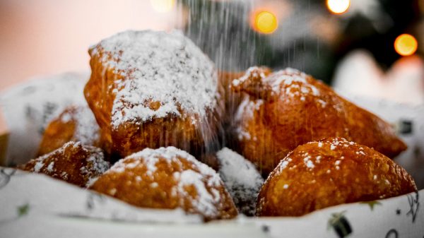 Foto van oliebollen die met poedersuiker worden bestrooid