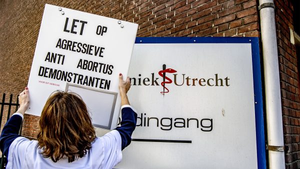 Dokter hangt bord op met de tekst 'let op aggresieve anti abortus demonstranten'' voor een abortuskliniek