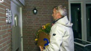 Thumbnail voor Winston Gerschtanowitz staat lang met bloemen en koffertje voor dichte deur in 'Miljoenenjacht'