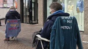 Thumbnail voor Kitty verstelt kleding op een klapstoel in de winkelstraat: 'Koop niet méér, maar repareer'