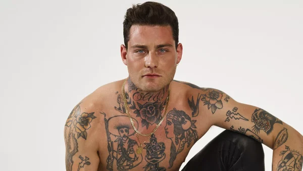 Douwe Bob kijkt recht de camera in, zonder shirt met zichtbare tattoos