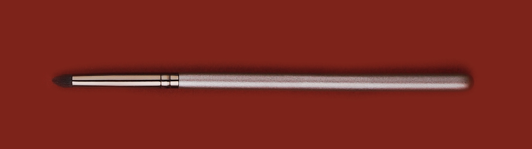 Een pencil brush op een donkerrode achtergrond make-upkwasten