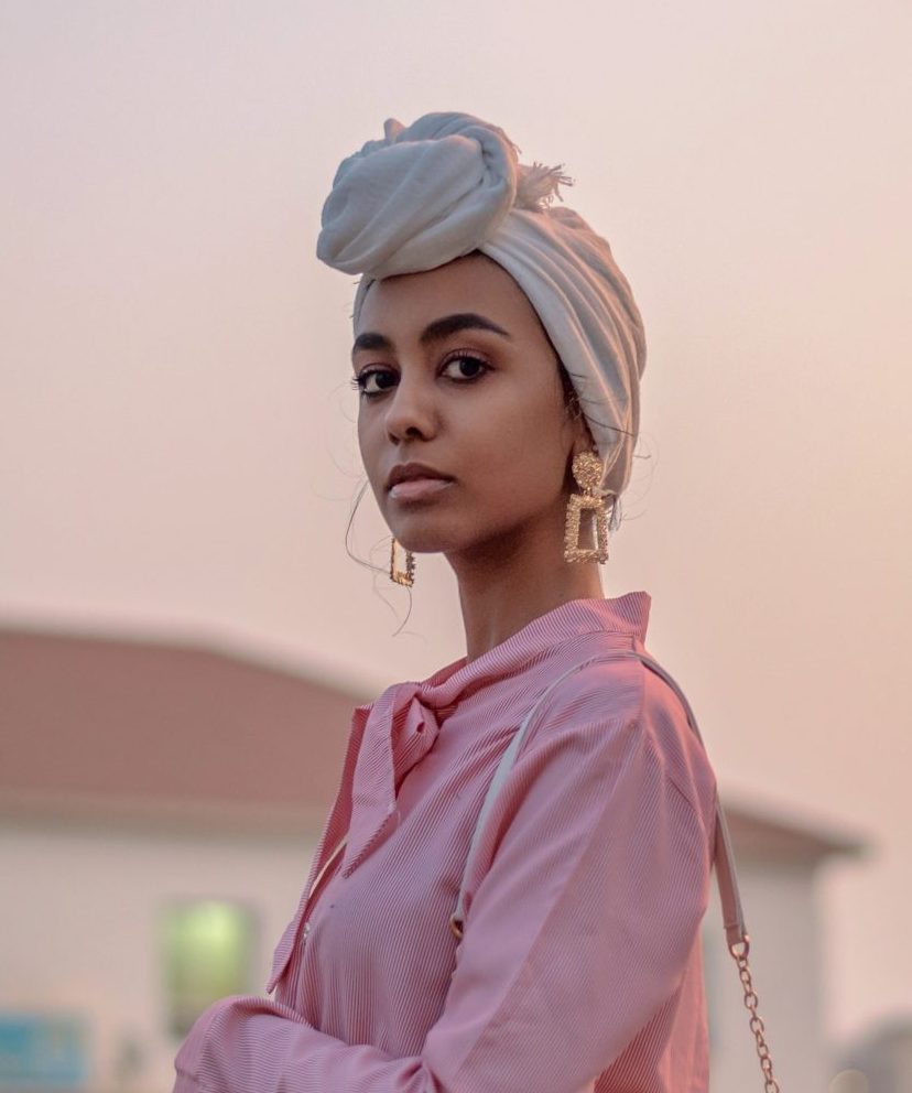 Vrouw met Barbie roze blouse en gouden oorbellen voor een roze achtergrond