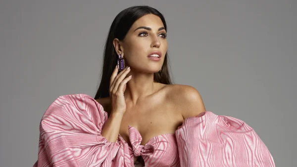 Yolanthe Cabau in een roze jurk voor een grijze achtergrond