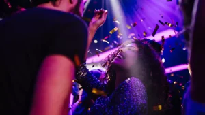 Vrouw danst uitgelaten in de club, met paars licht en confetti