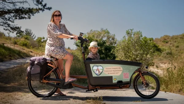 Moeder en kind in een fiets in de duinen.