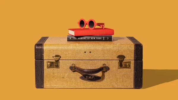 Koffer en een rode zonnebril op een oker gele achtergrond