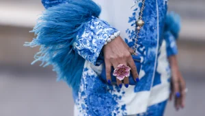 Valentino pak met blauwe tekeningen en veren, een hand met een bloemenring op straat
