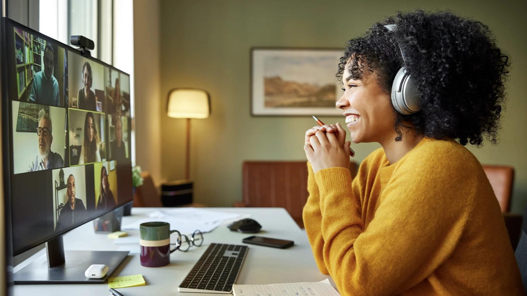 Vrouw zit thuis achter haar computer in een teams meeting met een koptelefoon op