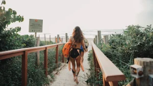 Vrouw loopt met surfboard naar het strand toe