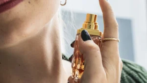 Close up van een vrouw die parfum op haar hals spuit.