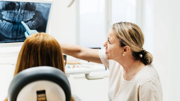 Vrouw zit bij de tandarts terwijl ze een foto van haar gebit ziet