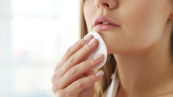 Vrouw verwijdert make-up met make-up removers op een wattenschijfje.