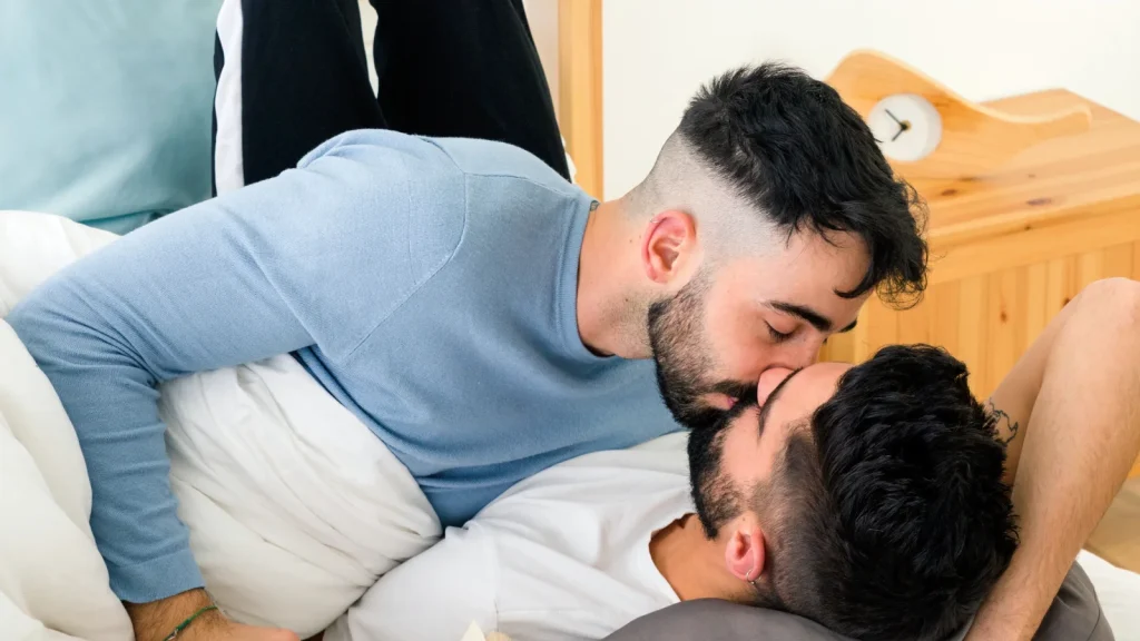 Twee mannen geven elkaar een zoen op bed. Omar downloadde een app