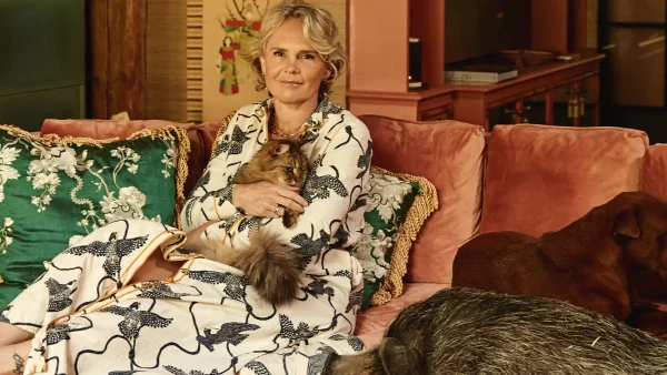 Reineke Antvelink zit op een roze stoel met een hondje in haar armen en een varken naast haar | Binnenkijken bij de interieurontwerper