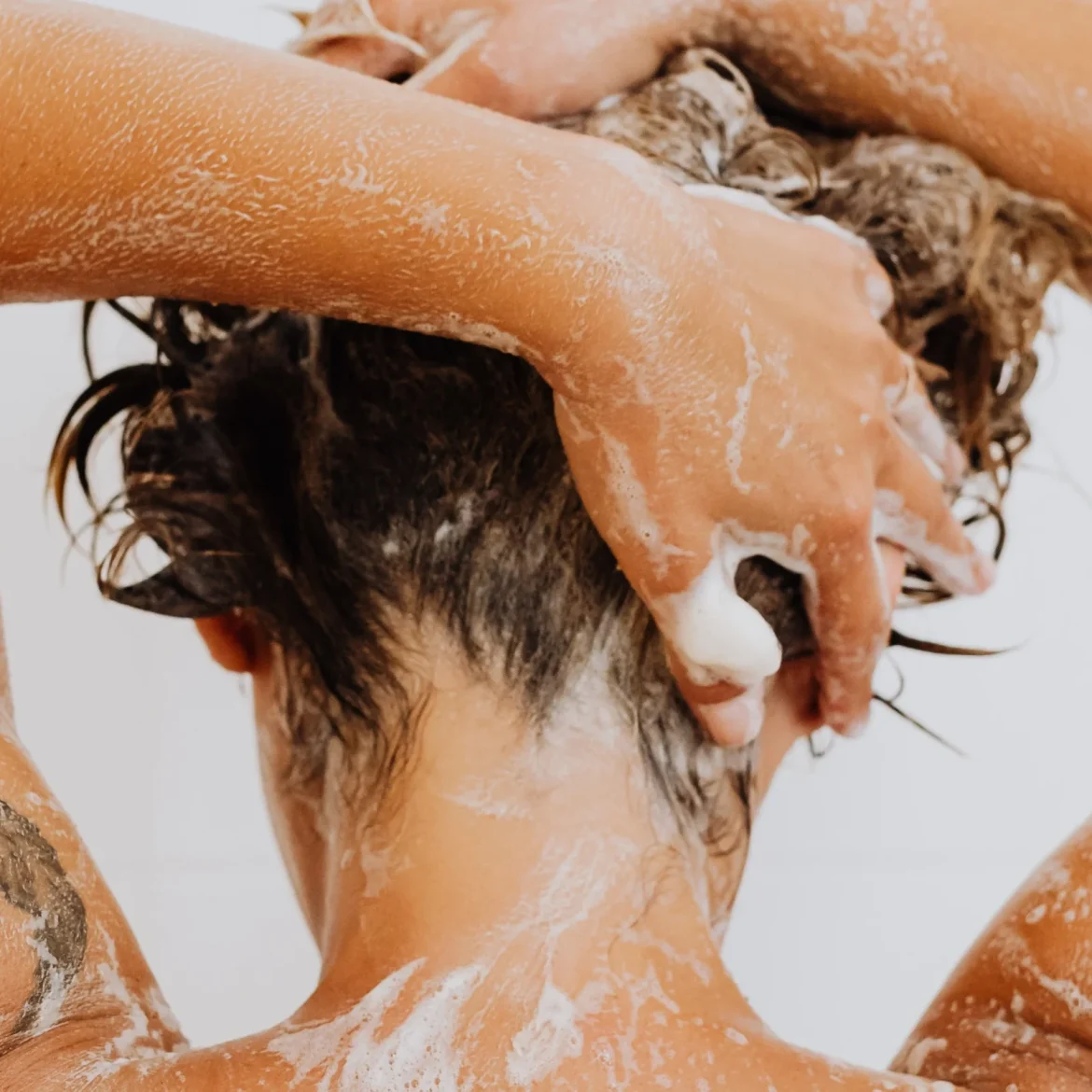 Vrouw wast haar haren met shampoo