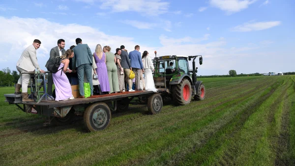 Gasten van bruiloft liften met tractor op boerderij mee