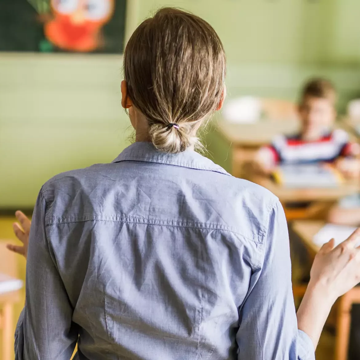 Eefjes man sliep met juf van kinderen: Schoolpleinroddels klopten | Foto: je ziet de rug van een juf die een klas vol jonge kinderen les geeft