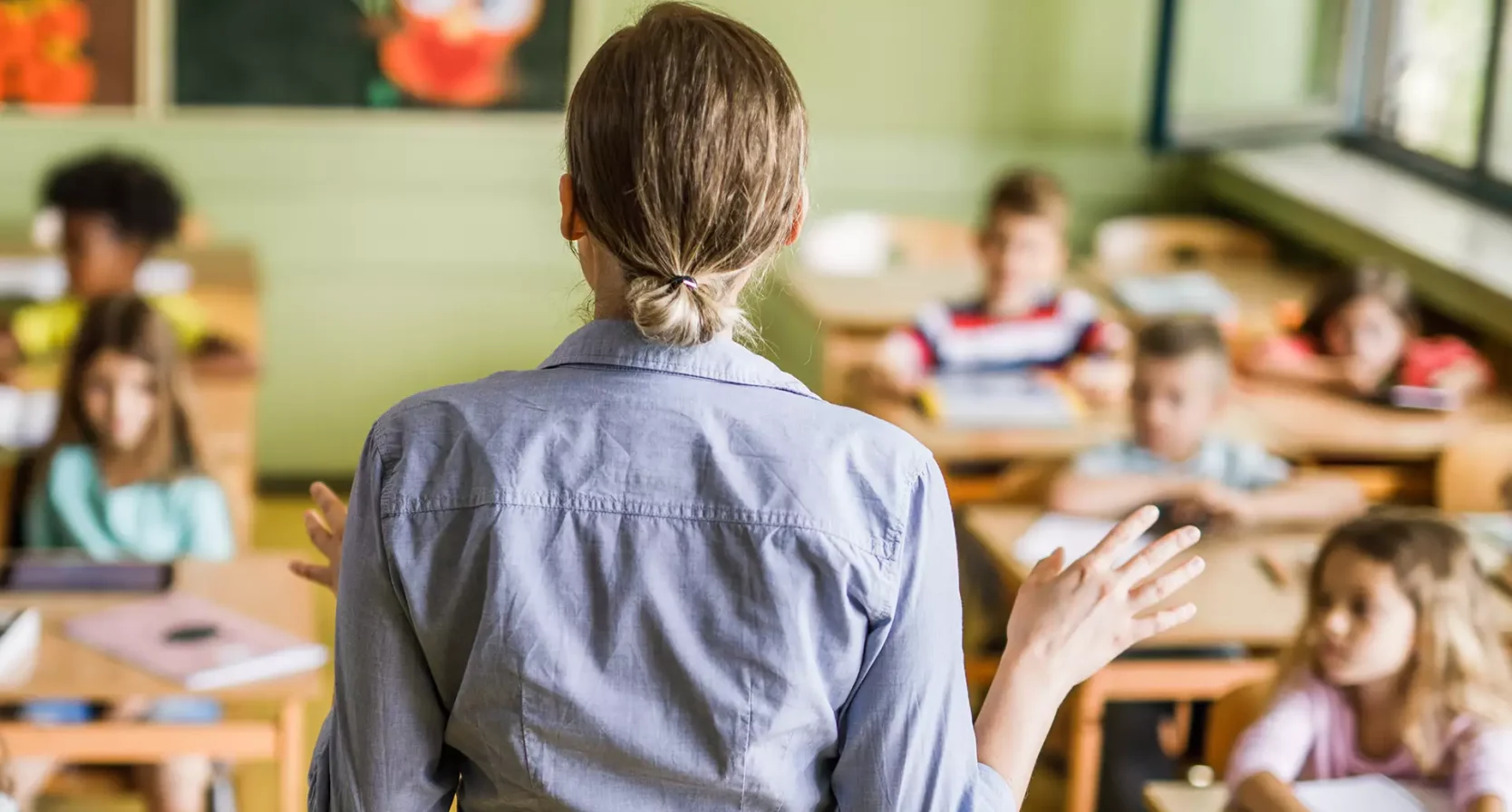 Eefjes man sliep met juf van kinderen: Schoolpleinroddels klopten | Foto: je ziet de rug van een juf die een klas vol jonge kinderen les geeft