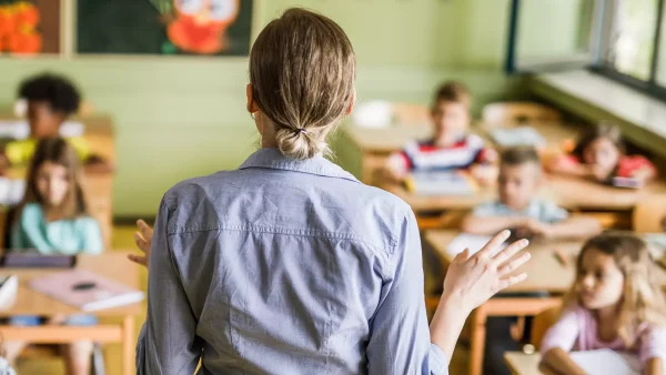 Eefjes man sliep met juf van kinderen: Schoolpleinroddels klopten | Foto: je ziet de rug van een juf die een klas vol jonge kinderen les geeft