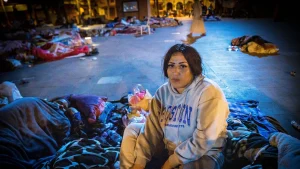 Mevrouw zit na de aardbeving op een plein met dekens