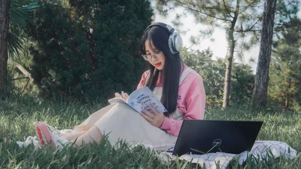 Vrouw zit in het park met haar laptop