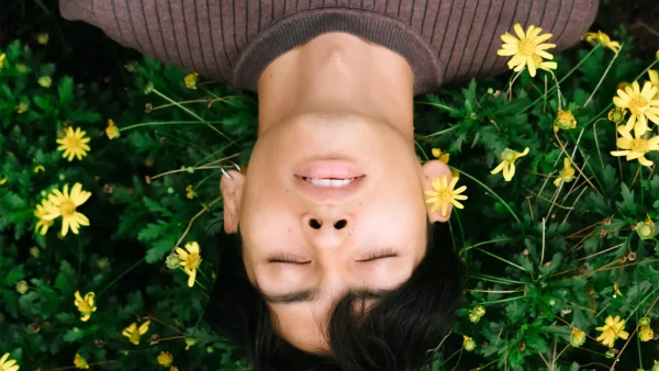Jonge man ligt met ogen dicht in bloemenveld. Artikel over uitvaart en wensen.