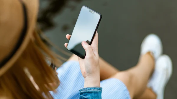 vrouw houdt telefoon vast met daarop ai-beelden