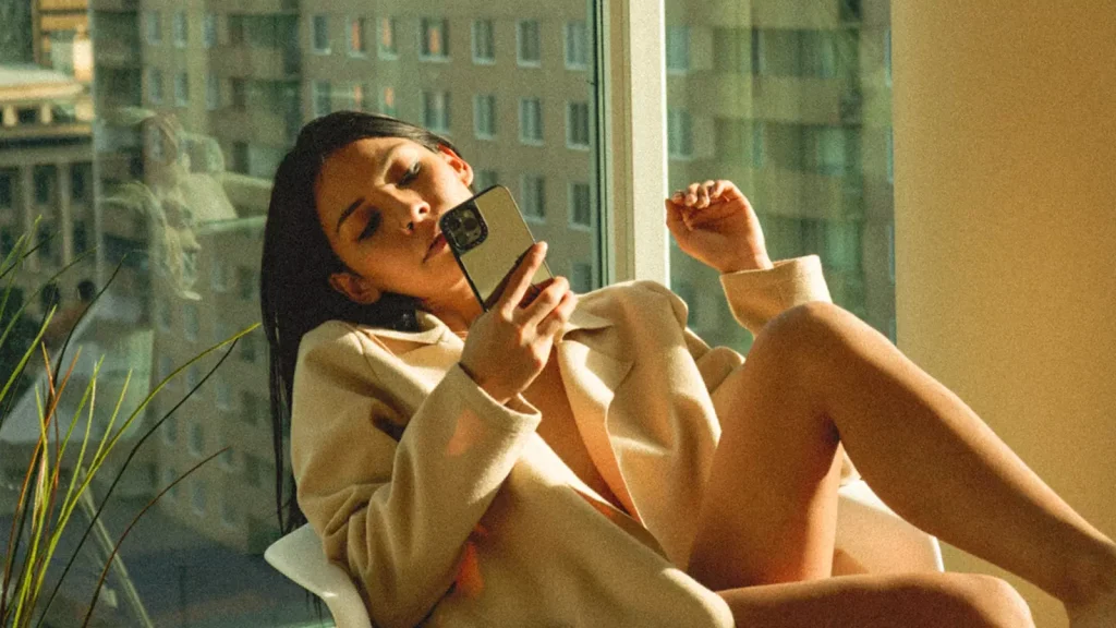 Vrouw zit in stoel met telefoon in hand