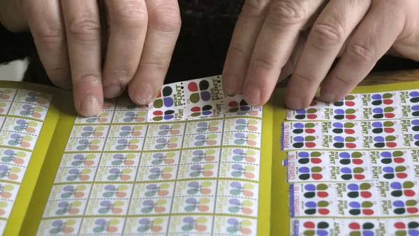 Vrouw plakt koopzegels in spaarboekje