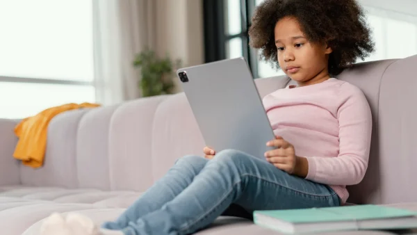 Jong meisje kijkt oorlogsbeelden op sociale media op haar tablet op de bank