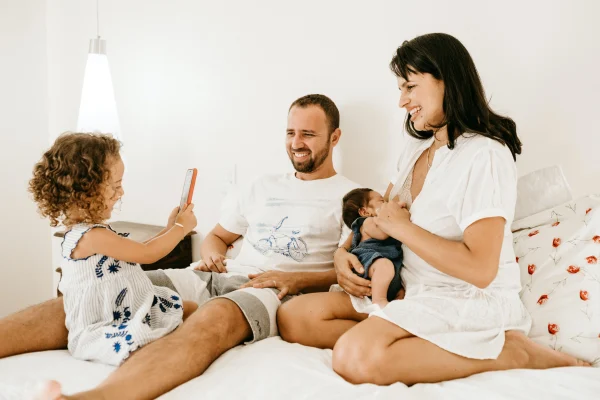 Man, vrouw en twee kinderen zitten op een bed