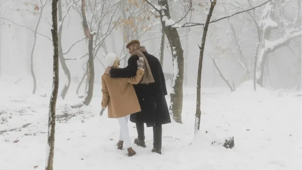 Een man en vrouw lopen gearmd door een winters landschap, Winter Vol Liefde