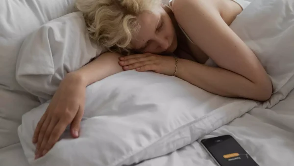 Vrouw in bed snoozen telefoon