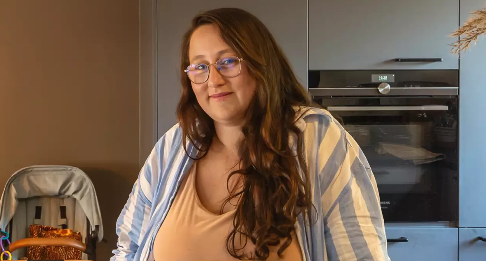 Huisvrouw Daniëlle poseert in haar keuken, en draagt een gele top met gestreepte blouse eroverheen