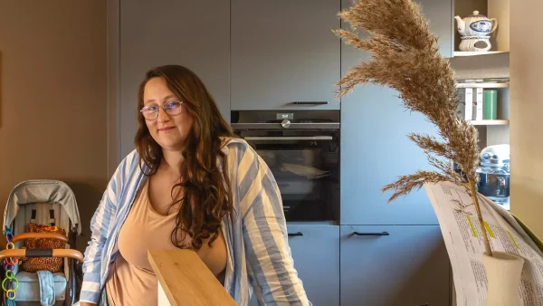 Huisvrouw Daniëlle poseert in haar keuken, en draagt een gele top met gestreepte blouse eroverheen