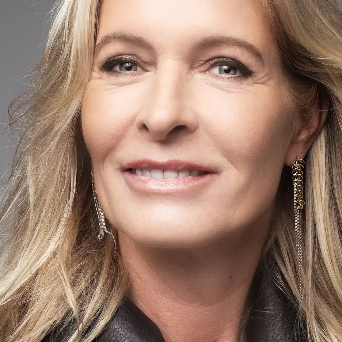 Mariska Bauer poseert voor een grijze achtergrond en lacht in de camera