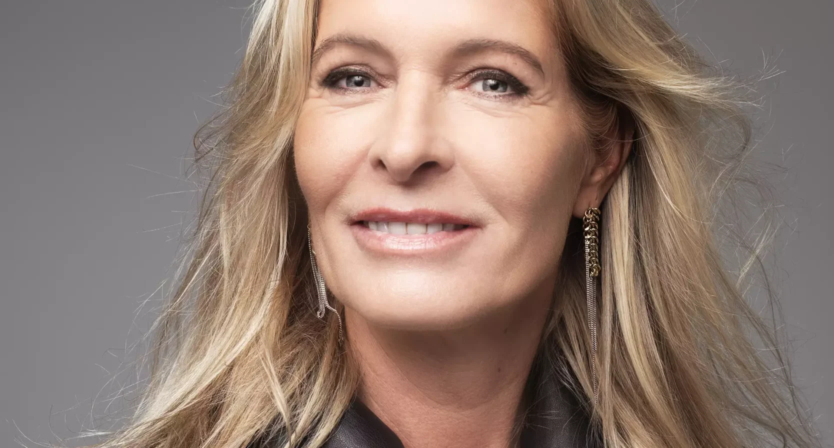 Mariska Bauer poseert voor een grijze achtergrond en lacht in de camera