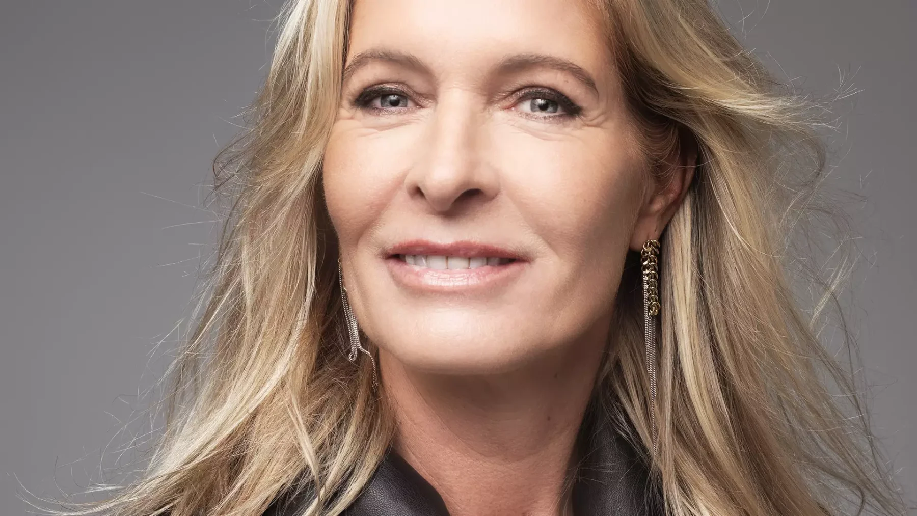 Mariska Bauer poseert voor een grijze achtergrond en lacht in de camera