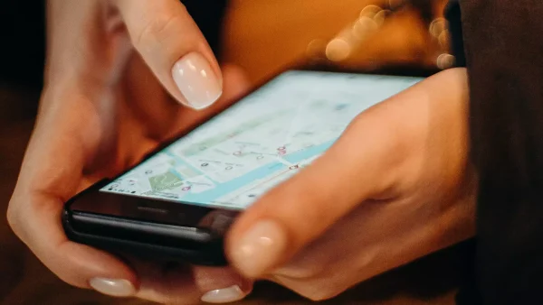 Vrouwenhanden houden telefoon vast met daarop Google Maps
