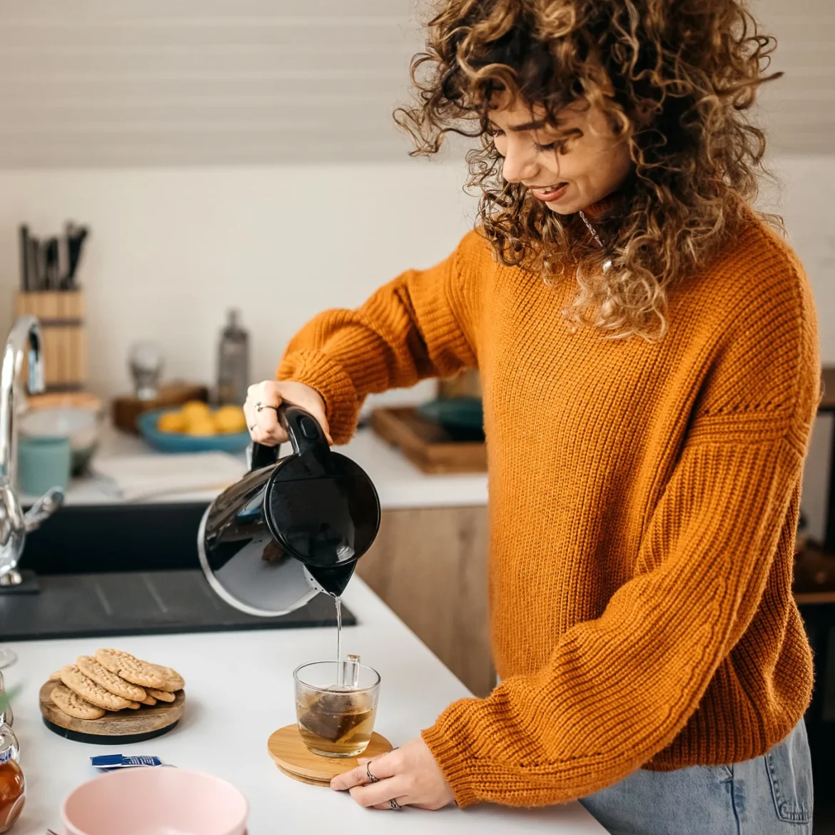 Een vrouw schenkt in de keuken haar thee in met een waterkoker