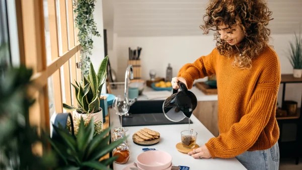 Een vrouw schenkt in de keuken haar thee in met een waterkoker