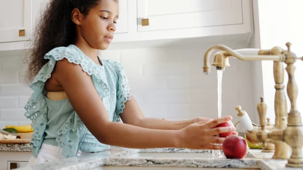 Meisje is haar appel aan het wassen onder de kraan