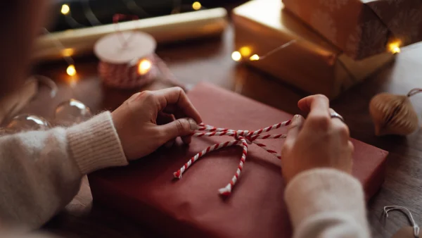 Een vrouw doet een strik om een van de decembercadeaus | Eén op vier Nederlanders gooit decembercadeaus ongebruikt weg