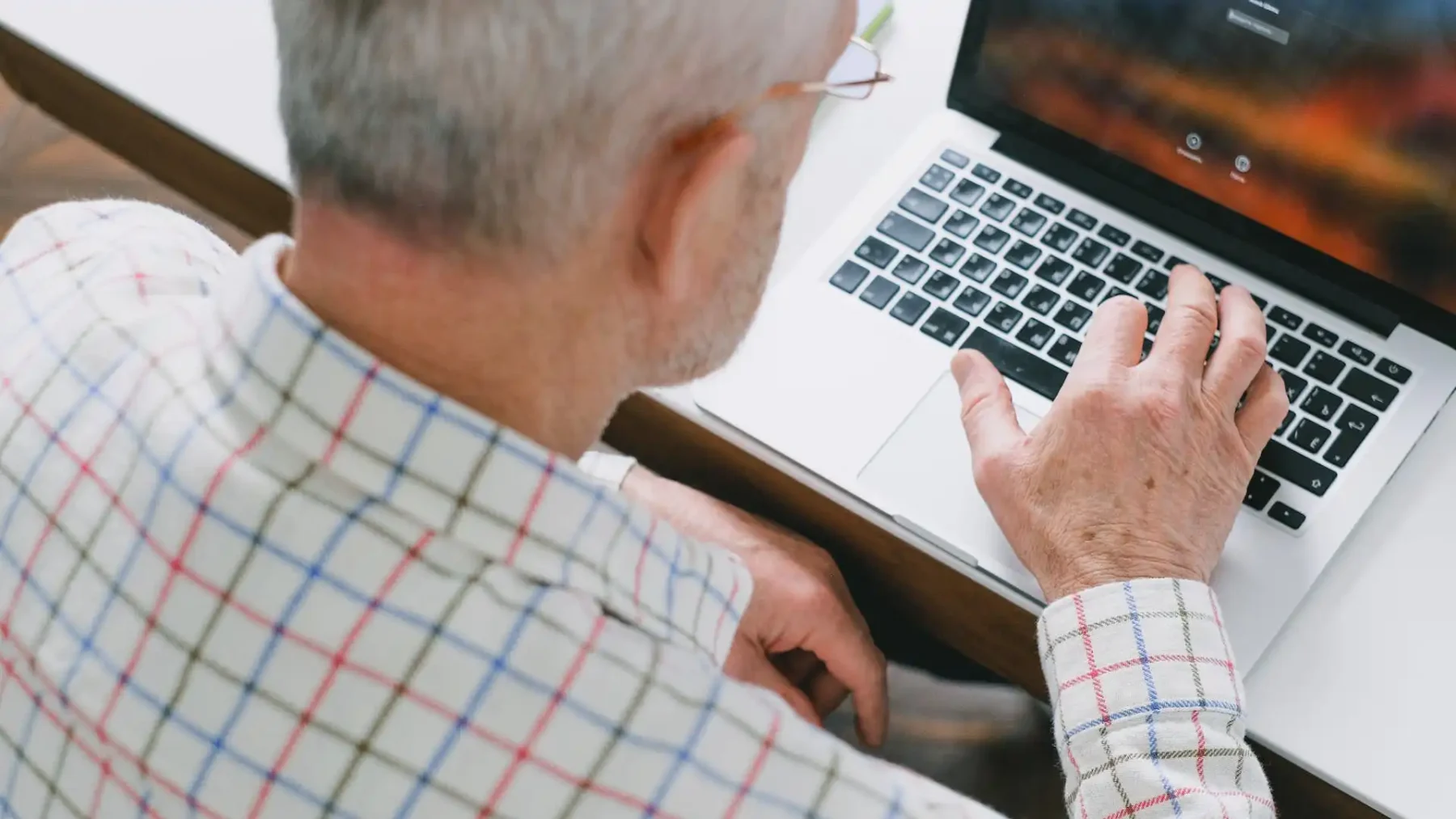 Foto van een oudere man achter een laptop } Datingfraude
