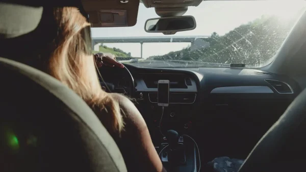 Afbeelding van een vrouw met lange haren achter het stuur van een auto